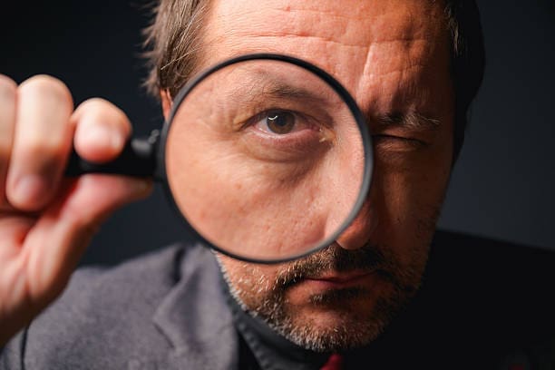 man looking through a magnifying glass hire a private eye